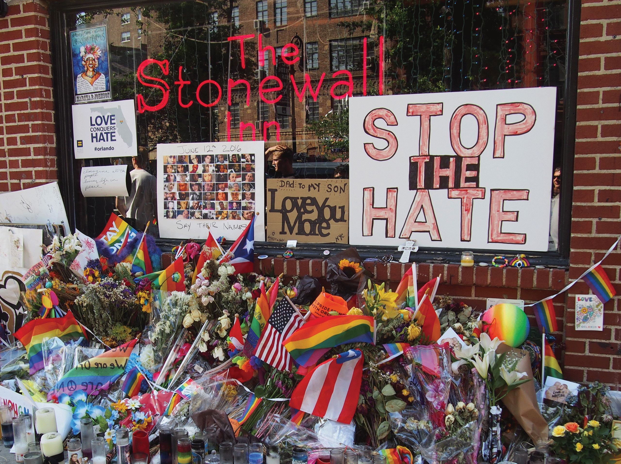 An image of the outside of Stonewall Inn in modern times, covered in rainbow flags and pride memorabilia.